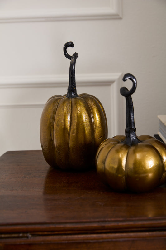 Two brass-finish cast aluminum Totem Pumpkins in squattier and taller sizes, with antique gold finish, ideal for autumn décor and seasonal displays.