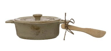 Ceramic cookware set with a lid and wooden spatula on a white background