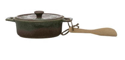 Ceramic pot with lid and wooden spoon on a white background