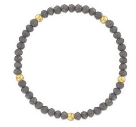 A beaded stretch bracelet featuring dark gray round beads separated by small gold spacer beads, shown on a plain white background.