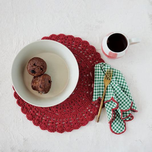 Bowl with cookies, cup of coffee, and cutlery on a red doily on a white surface