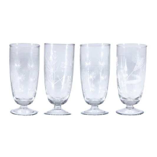 Set of four clear glass tumblers with starburst patterns on a white background