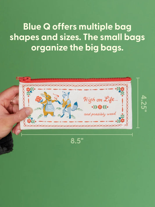 A hand holds a small illustrated zip pouch against a green background with text explaining Blue Q bag organization. The pouch is cream with red trim and a whimsical bunny-and-fox design, with dimension labels showing 8.