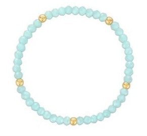A beaded stretch bracelet featuring light blue faceted beads separated by small gold spacer beads, shown on a plain white background.