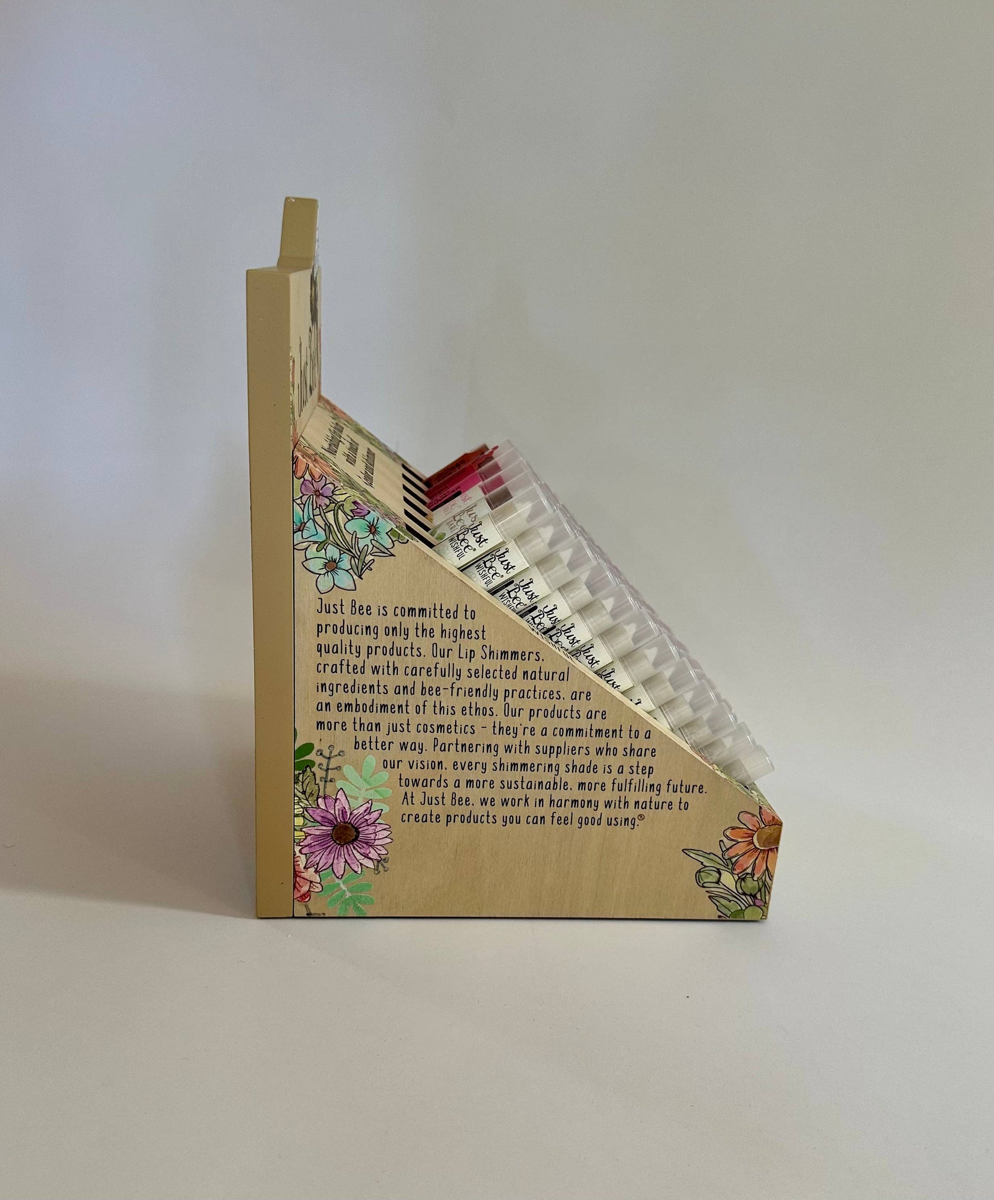 Wooden product stand packaging with floral designs and text on a white background
