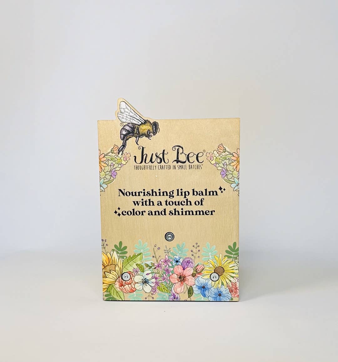 Lip balm packaging with floral design and bee illustration on a white background
