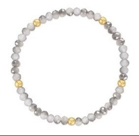A beaded stretch bracelet featuring light gray and white marbled beads with alternating polished gold accent beads, shown on a plain white background.