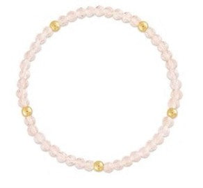 A beaded stretch bracelet made of light pink faceted beads with small gold spacer beads, shown on a plain white background.