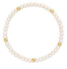 A beaded stretch bracelet featuring white freshwater pearls and small gold spacer beads, shown on a plain white background.