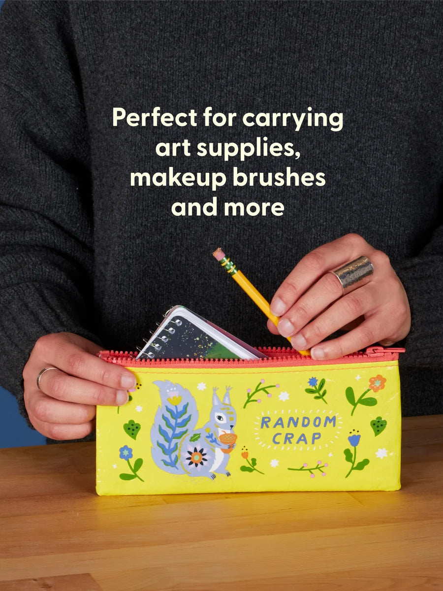 Person holding a yellow pencil case with a cartoon squirrel design, text 'Perfect for carrying art supplies, makeup brushes and more' on a dark sweater.