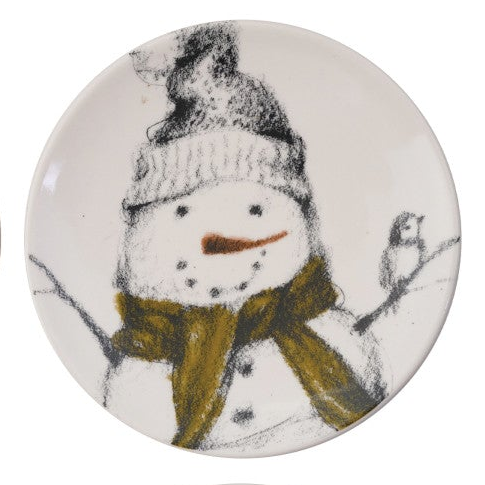 A round white ceramic plate featuring a whimsical hand-drawn style illustration of a snowman wearing a gray knit hat and a mustard yellow scarf, with a small bird on a branch.