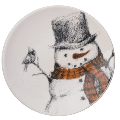 A round white plate featuring a whimsical hand-drawn style illustration of a snowman wearing a black top hat and an orange-brown plaid scarf, with a small bird on a branch to the left.