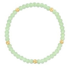 A beaded stretch bracelet made of light green faceted beads with small gold spacer beads, shown on a plain white background.