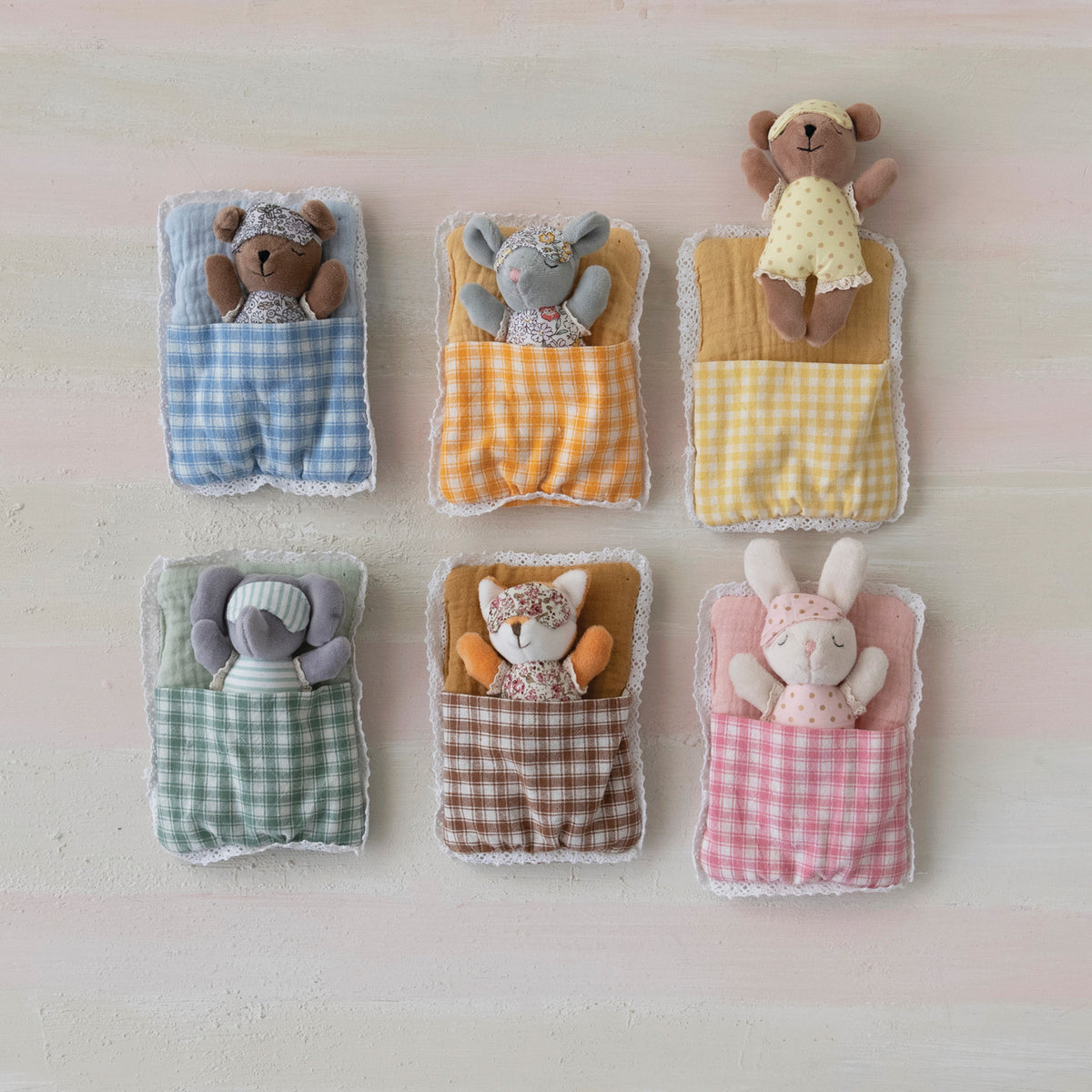 Set of small plush toys in fabric pockets on a light background