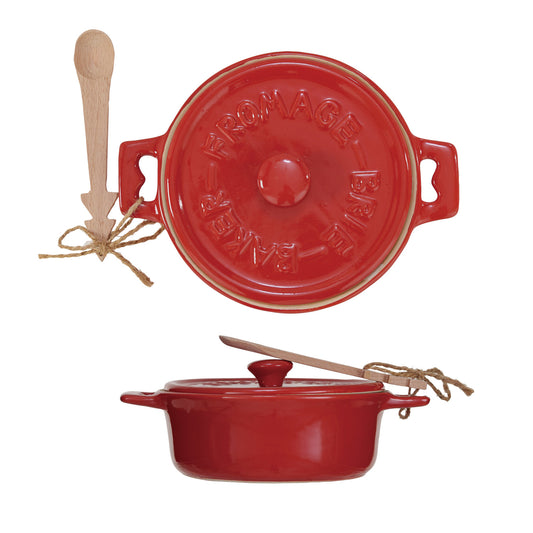 Red ceramic baking dish with wooden spoon on a white background