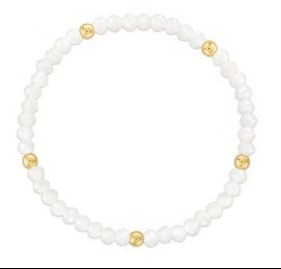 A beaded stretch bracelet made of small white beads with five evenly spaced gold round spacer beads, shown on a plain white background.