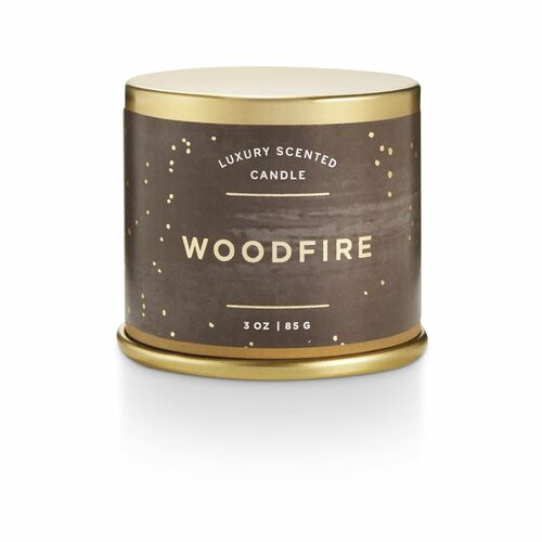 Illume Woodfire Demi Vanity Tin candle with oak moss, fir needle, and cinnamon scent. Compact, vegan, plant-based candle in recyclable tin with textured full-wrap label and metallic details.