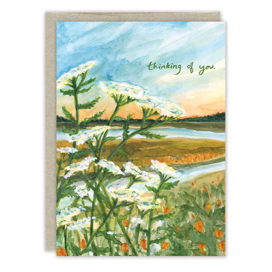 Greeting card with a scenic landscape featuring flowers and text 'thinking of you'.