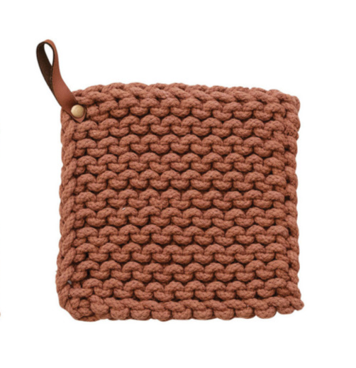 A square, cotton crocheted pot holder in the color rust with a small brown leather pull tab.