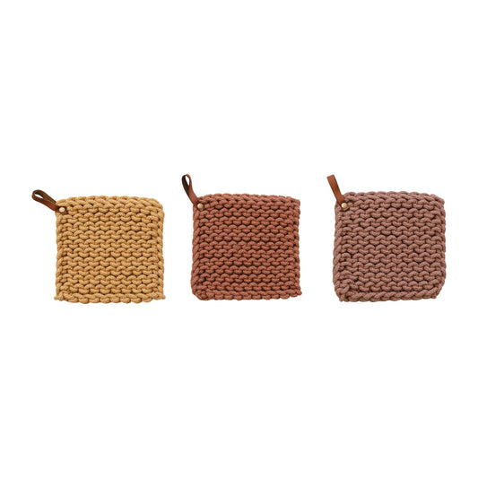 Three crocheted pot holders in mauve, mustard and rust.