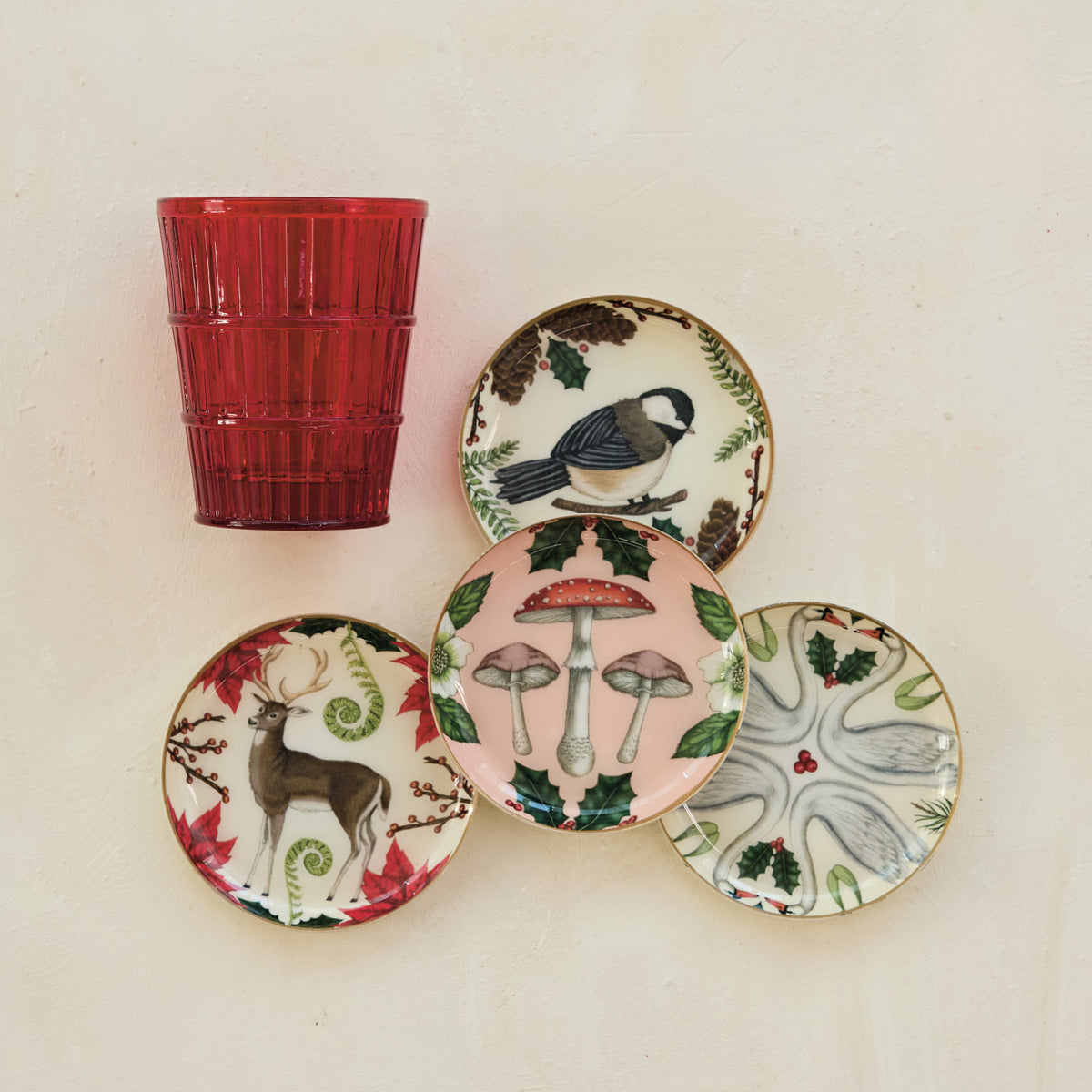 Petite enameled metal botanical trinket dishes and coasters with colorful nature illustrations and gold-toned rims.