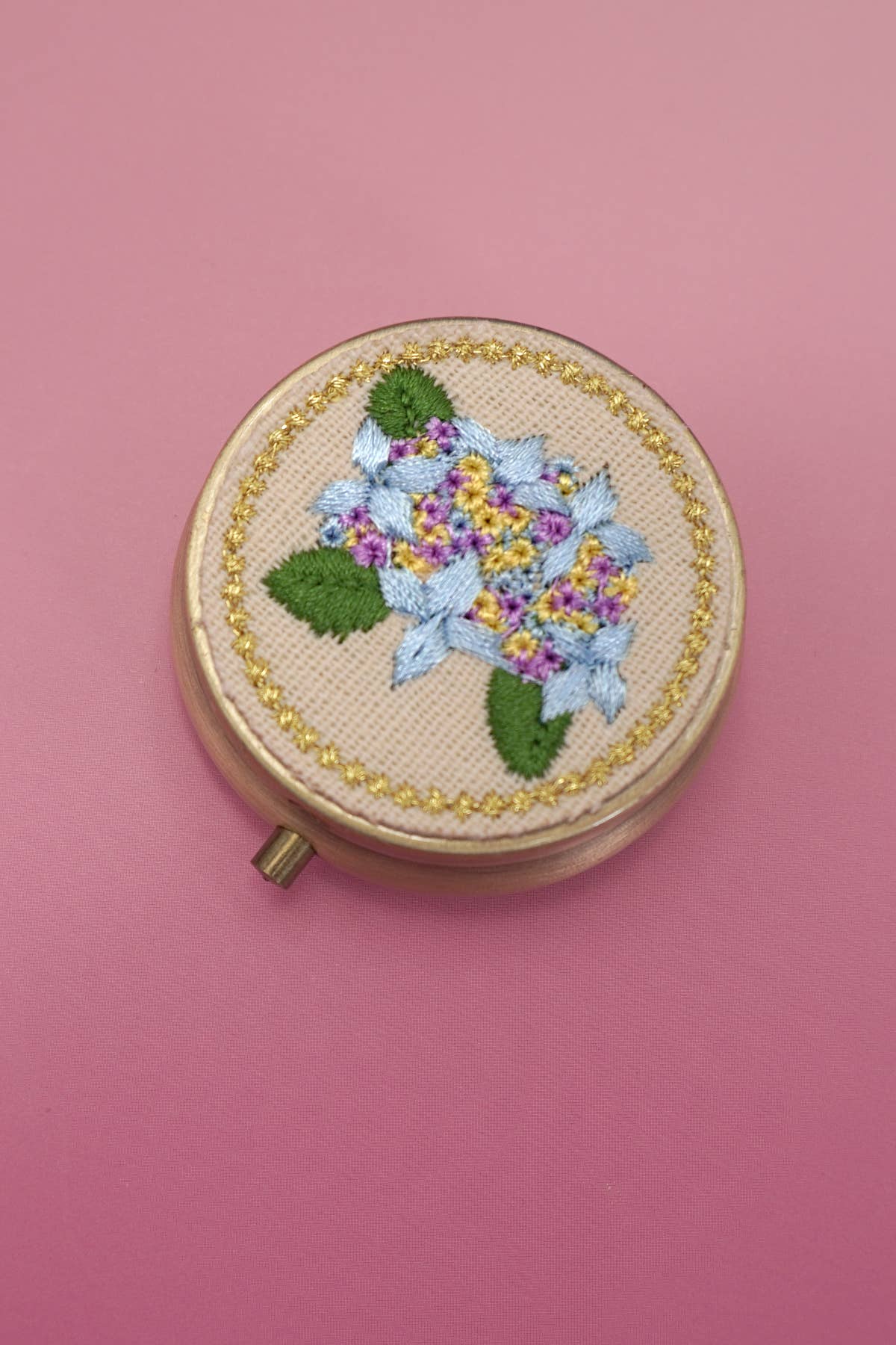 Embroidery hoop with floral design on a pink background