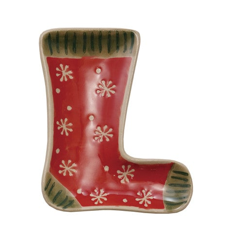 A Christmas stocking-shaped ceramic trinket dish with a glossy red body, white snowflake pattern, and green striped cuffs and toe.