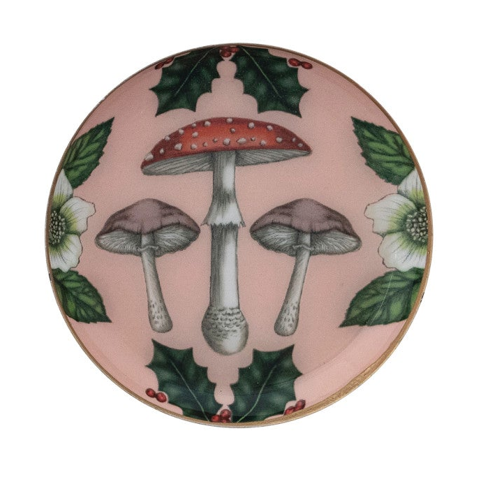 Round enameled metal trinket dish with mushroom and botanical illustration and gold-toned edge.