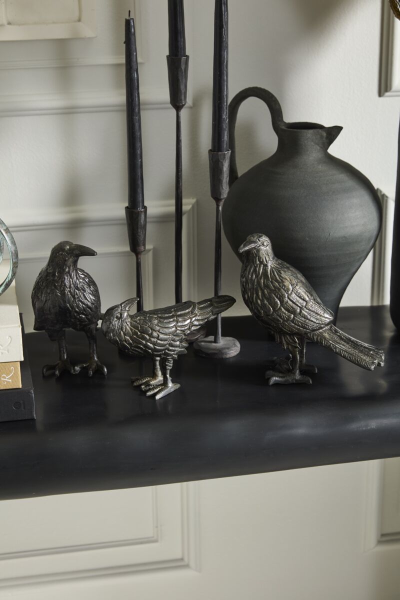 Nevermore raven figurine displayed among books and collected decorative objects