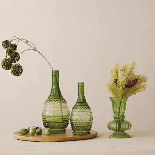 Three green glass vases on a wooden stand with decorative elements.